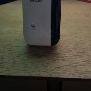 Vit trådlös repeater - Säljer en vit trådlös repeater med WPS-knapp och LAN-port. Perfekt för att förstärka ditt Wi-Fi-signal hemma. Enkel att installera direkt i vägguttaget.
