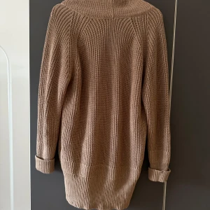 Beige/brun stickad kofta med knappar - Säljer en mysig beige/brun stickad kofta i 100% bomull. Koftan har långa ärmar och knappar framtill samt två praktiska fickor. Koftan är halvlång, en bit nedanför ändan. Koftan är sparsamt använd och i jättefint skick. Storleken är lite overzise.
