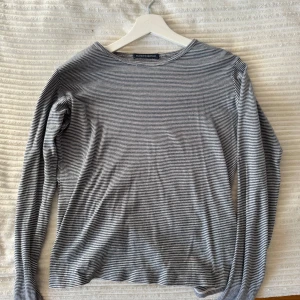 Randig långärmad tröja från brandy Melville - Säljer en stilren och bekväm randig långärmad tröja från brandy. Tröjan har en klassisk rund hals och är perfekt för lager-på-lager under kyligare dagar. Den är i en neutral färgskala med smala ränder i svart och vitt.