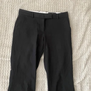 Svarta kostymbyxor från Stockh LM - Snygga svarta kostymbyxor från Stockh LM. De har en klassisk design med raka ben och hällor för bälte. Perfekta för en stilren look.