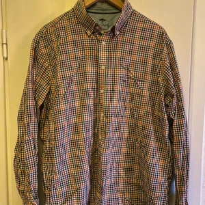 Rutig skjorta från Fynch-Hatton - Säljer en snygg rutig skjorta från Fynch-Hatton i premium cashmere finish. Skjortan har långa ärmar och knappar framtill. Perfekt för en stilren look med sina klassiska rutor i flera färger.