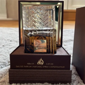Khamrah Oahwa Eau de Parfum - Elegant parfym från Lattafa, Khamrah Oahwa, i en lyxig glasflaska med geometriskt mönster. Flaskan är placerad i en stilren brun förpackning. Innehåller 100 ml Eau de Parfum. Priset kan diskuteras 