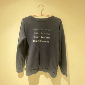 Mörkblå sweatshirt från Peak Performance - Säljer en stilren mörkblå sweatshirt från Peak Performance med tryck på framsidan. Tröjan har långa ärmar och en rund halsringning. Perfekt för en avslappnad look. Nypris 700kr, Hör av dig vid intresse!