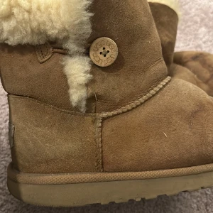 Beiga uggs med knapp - Beiga uggs med knapp, lite missfärgade framtill men går enkelt att ta bort med skoborste inga övriga skador.