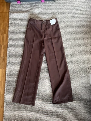 Oanvända byxor - Bruna byxor från uniqlo. Oanvända med lappar kvar. Skulle säga att dom är ganska stora i storlek