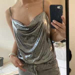 Silvrig partytopp - Skitsnygg partytopp i silverfärg. ”Cowlneck” i fram och ganska låg i ryggen.