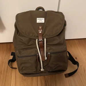 Sandqvist Ryggsäck - Sandqvist Ryggsäck i fin olivgrön färg. Använd endast ett antal gånger, endast lite sliten på framfickorna, annars som ny!