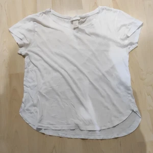 Basic vit T-shirt - En enkel helt vit T-shirt. Rundad i neder kanten