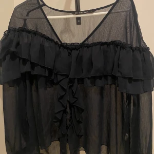  Genomskinlig blus - Loose fit, genomskinlig svart blus med volanger Använd helst köp nu!