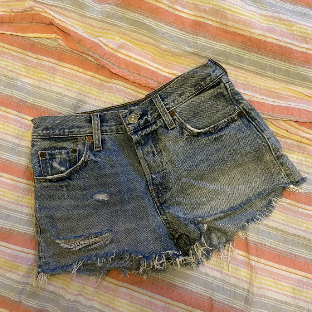Blå, korta jeansshorts från Levis med slitningar, köpta i New York och använda väldigt få gånger. Storlek W24. Shorts.