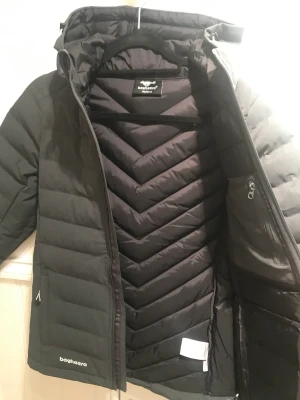 Vinterjacka 146/152  - Hej ny och oanvänd jacka med prislappen på. Märket är Bagherra och jackan är väldigt lätt och skyddar mot vind och regn. Färgen är gråsvart och priset låg på 1295 kr när den köptes och säljer den mycket billigare.   