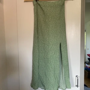 Blommig långkjol - Använd vid ett tillfälle. Har dragkedja o slits i sidan. Går ner över vaden på mig som är 166 cm.Hör gärna av dig vid frågor eller för fler bilder. Köpare står för frakt.