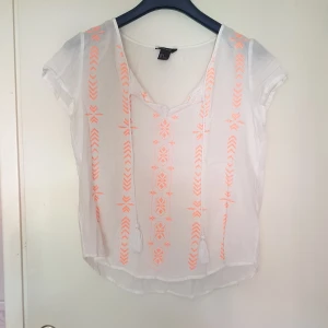 Blus - En vit blus från lindex med noeon orangea detaljer fram till. Även band fram som går att knytas