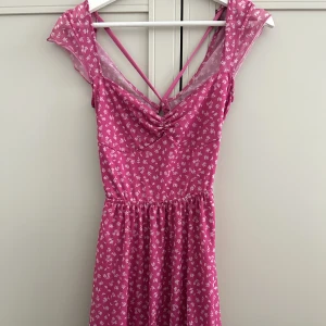 Blommig klänning med öppen rygg - Jättesöt blommig klänning med öppen rygg och knytning. Använd 1 ggr!