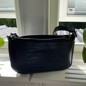 Svart väska - Svart väska med fake skinn. Tre fickor på insidan, två utan dragkedja och en med dragkedja 