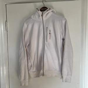 Vit sail racing hoodie i storlek M.  Inga skador, men små fläckar som troligen går att trötta bort. Har ej testat själv eftersom hoodien blivit för liten. Tveka inte på att skicka DM vid frågor.