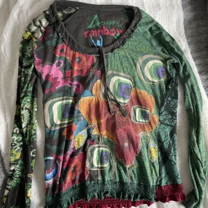 Desigual topp  - Flerfärgad Desigual topp. Väldigt snyggt och skön. Har guld tråd på framsidan och en liten rosett (se bild) Skriv vid frågor!