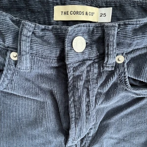 Manchesterbyxor The Cords & Co stlk XS - Blå byxor i manchester, korta i modellen, stlk XS/34 (26 tum)  Minimalt använda. Se bild för hur byxkanten är, ej ändrats efter köp. 