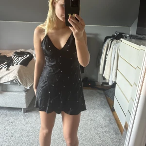 Svart satinklänning med glitterdetaljer - Svart satinklänning i storlek M från Zara som inte säljs längre! En väldigt fin klänning som jag använde på nyår förra året och kommer inte längre till användning. 