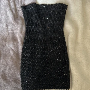 klänning - säljer denna glittriga bandeau klänningen då den aldrig kommer till användning. Aldrig använt. Skönt material inuti med material så den inte åker omkring