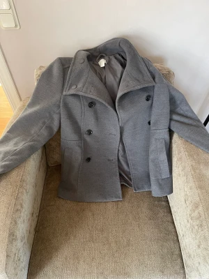 Grå kort kavaj/kappa - En grå skepparkavaj från hm i mycket gott skick. Storlek 42 men skulle nog säga att den är lite liten i storleken och snarare 38/40. Hyfsat varm så passar perfekt nu för hösten och vintern😁❤️