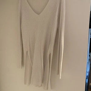 Lång vit tröja med slits på båda sidor - Ribbad, vit tröja med v-ringning. Slits från ungefär höfter och ner en bit på låret. Bara att fråga för bättre bilder.