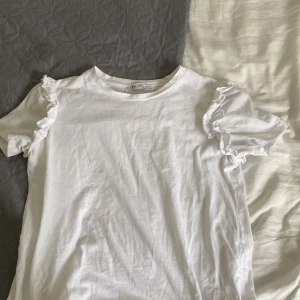 Vit t-shrt - Jag säljer en jätte söt hit t-shirt med volanger på armarna! Fint skick! Strl S från zara! 