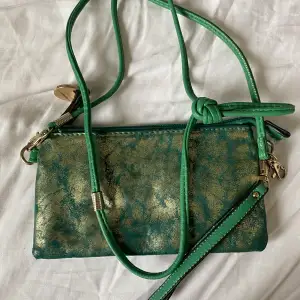 Grön/guld handväska med axelband. En karbinhake trasig men kan användas på båda sätt ändå. 