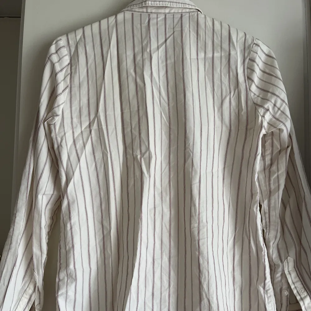 Figursydd beige skjorta med lila ränder från HM x Giuliva Heritage.  Smäcker och ger ett ”dressat” intryck, men kommer tyvärr inte till användning hos mig. Passar xs-s. Är tyvärr inte struken vid försäljning. . Skjortor.
