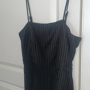 Randig klänning  - Svart klänning med tunna vita ränder. Går ovanför knän