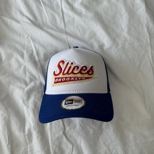 New era keps  - New ers trucker keps med ”Slices Brooklyn” broderi framtill. Fint skick. Köparen står för ev frakt 