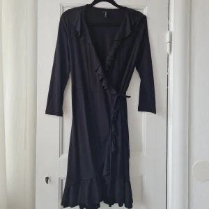 Omlottklänning  - Svart omlottklänning från Vero Moda. Lite kortare i ärmarna och har volanger nedtill