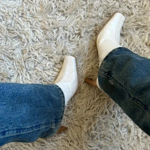 Vita stövletter med fyrkantig tå - Vita stövletter i syntetmaterial, sitter tight och slutar halvvägs på vaden. Bekväma att gå i.  