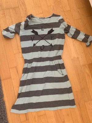 Klänning - Säljer denna barnklänning från kids by Lindex. Dom är i nyskick och har fickor. Den är i storlek EUR 158/164 och nypris är runt 180kr säljer nu för 80kr