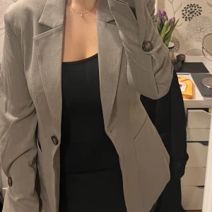 Blazer från NA-KD - Säljer denna fina blazern från NA-KD i storlek 36! Aldrig använd och i superfint skick. Den är lite figursydd, så midjan framhävs väldigt fint i denna blazern! I verkligheten är färgen en blandning mellan kall brun & grå. Nypris 799kr, säljer för 350kr!💕