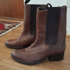 Stövlar  - Säljer mina stövlar i mörkbrunt skin med klack.  Använda ett tag är i bra skick och sulan syns knappt att de är använda.  Jätte sköna och snygga på.  Inga defekter och kommer från rök och djur fritt hem  Nypris 899