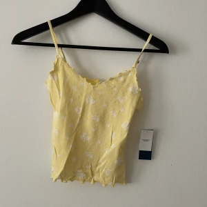 Somrigt linne - Somrigt linne i gult med vitt blommotiv. Storlek small