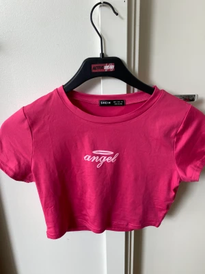 Rosa topp - Aldrig använd! Super fin croppad rosa topp med tryck. Strl S men stretchig så passar nog XS-M beroende på hur man vill den ska sitta!