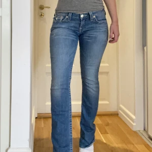 True Religion jeans - Lågt skurna jeans från True Religion. SUPERsköna. Saker att anmärka på: lite slitage vid byxben (se bild), dragkedjan är sönder men lätt fixat tror jag (den har hoppat ur), ca 6st stenar på rumpan har försvunnit (syns knappt). Strl 28 ev mer som 29