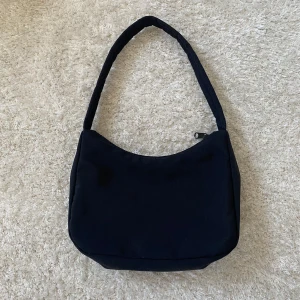 Liten väska från Gina Tricot - Svart liten väska från Gina Tricot helt oanvänd i nyskick. Har en liten ficka med dragkedja i väskan.