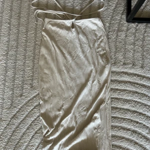 Lång kjol - Lång kjol med häftig snörning runt midjan. Kjolen är beige med ribbat mönster och slits på ena sidan. Jag är 175cm lång och den går till vristen. 