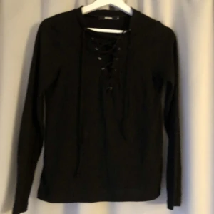 Tröja med snörning - Svart ribbad tröja från bikbok i stlk S med snörning i fram. Använd några gånger men i bra skick 💗