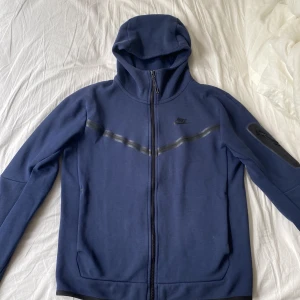 Nike tech mörkblå - Säljer min mörkblåa nike tech tröja då den inte kommer mycket till användning. Köpte här på Plick av en ägare som knappt använt den. Den är i väldigt bra skick utan några hål eller liknande. Köpare står för frakt. Kontakta gärna för fler frågor