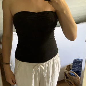 Tubtopp - En svart tubtopp med lite scrunch mellan brösten. Använd mycket så kan va lite sliten i tyget men annars i bra skick. Är längre i modellen men går att vicka upp. Osäker på storlek men passar mig som har S. Kontakta om ni vill ha mått.