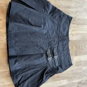 En kort svart kjol från Bondelid med skinnspännen fram. Superfin modell. Legat i garderoben några år därav skrynklig. 