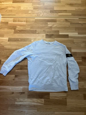 Stone Island Logo Crewneck - Riktigt snygg ljusblå/grå crewneck från Stone Island. Storlek L, använd men i mycket bra skick. Nypris ca 3000kr. Skriv för frågor eller fler bilder!