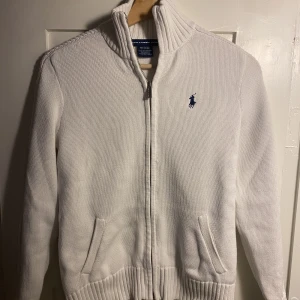 Stickad Ralph Fullzip - En stilig stickad tröja till vinter säsongen. Som man ser i bild två är armarna kabelstickad. Tröjan är i nyskick utan några defekter. Tröjan är i storlek S men passar också XS. Vid några frågor och funderingar så är det bara att skicka.