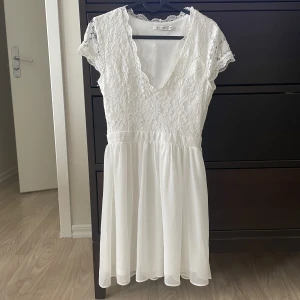 Vit klänning  - Säljer nu min studentklänning från Nelly som endast har använts 1 gång & är i nyskick. V-ringad med spets i toppen.  Köpare står för frakt 