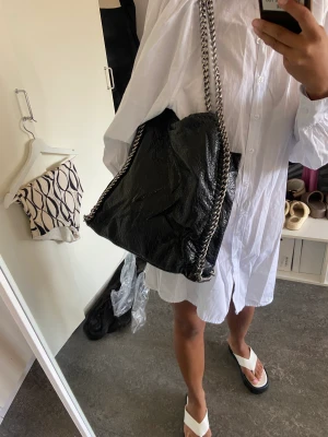 Svart väska med silver kedja  - Fint skick. Väska med silver kedja med fack utanför och innanför 