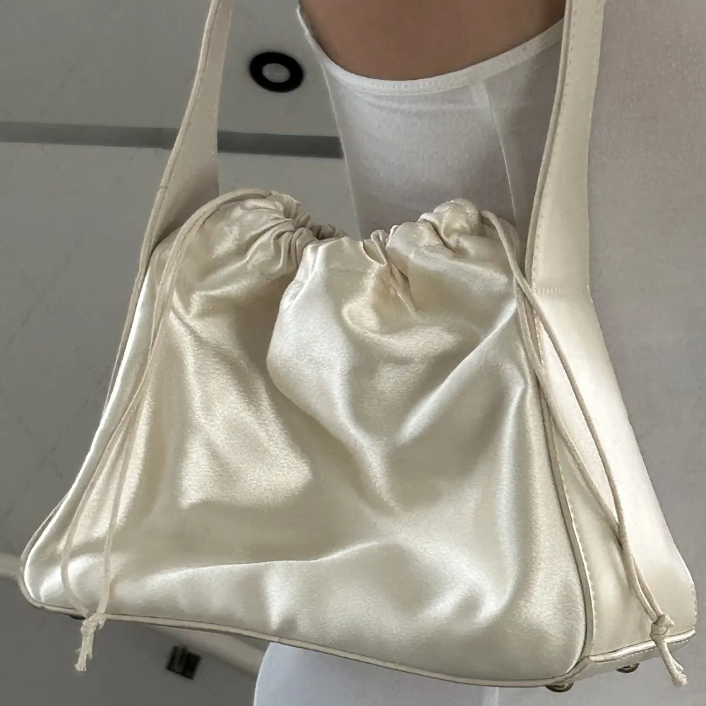 säljer denna väska i fin ljusbeige/créme silk ish material 🤍 materialet är i bra skick då jag knappast använt den :)‼️köpare står för frakten!. Väskor.